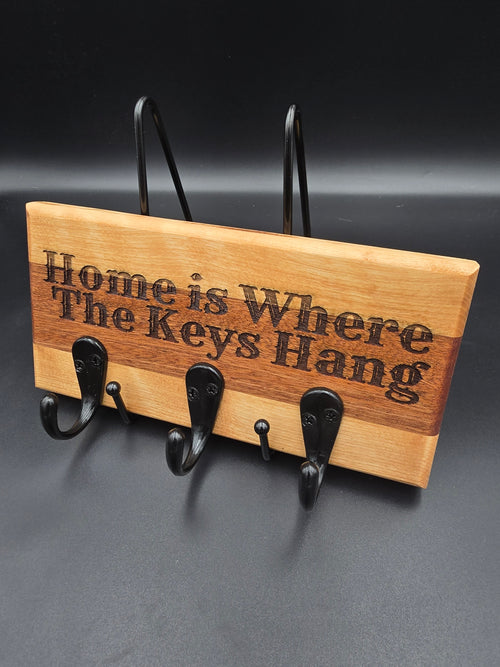 Wooden Key Holder laser engraved with "Home is where the keys hang" featuring mounting hardware and three black hooks