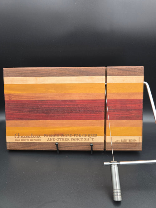 modern handcrafted wooden cheese board made from walnut, maple, rosewood, red heart and yellow heart, built in silver cheese slicer, perfect for charcuterie, cheese, and appetizers. Laser engraved with the phrase "charcuterie french word for cheese and other fancy shit"
