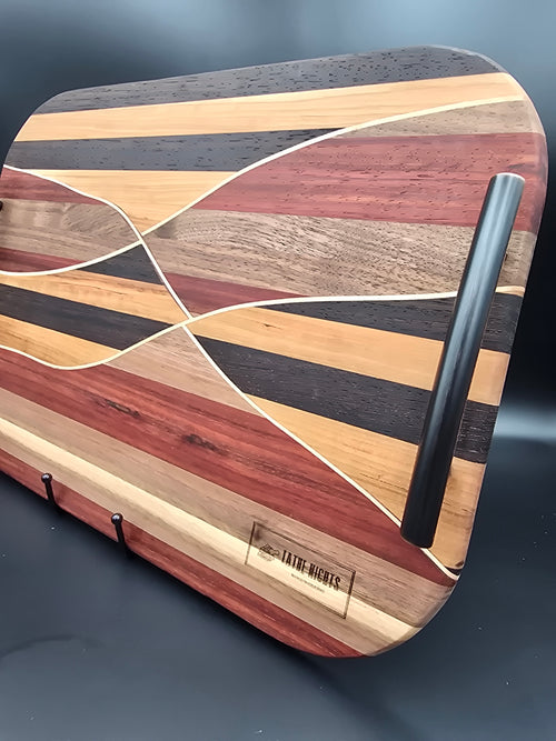 Wooden cutting board with a geometric pattern on a black background made with walnut maple padauk wenge and cherry