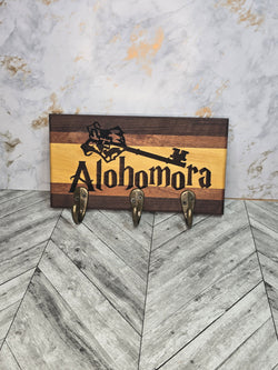 Wooden key hook laser engraved with "alohomora" made from walnut mahogany and yellow heart hardwoods, with three (3) gold hooks