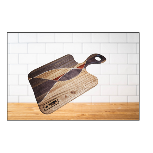 A wooden charcuterie board with a geometric pattern design, placed on a wooden surface with a white background.