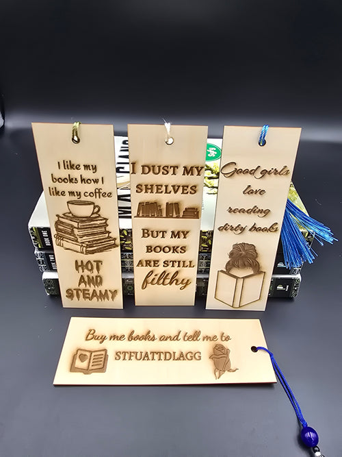 A collection of 4 laser engraved wooden bookmarks with colorful tassels that measure 6" x 2", standard bookmark size. Adult themed laser engraved phrases that read "i like my books how I like my cofee hot and steamy" "i dust my shelves but my books are still filthy" "good girls love reading dirty books" "buy me books and tell me to stfuattdlagg"
