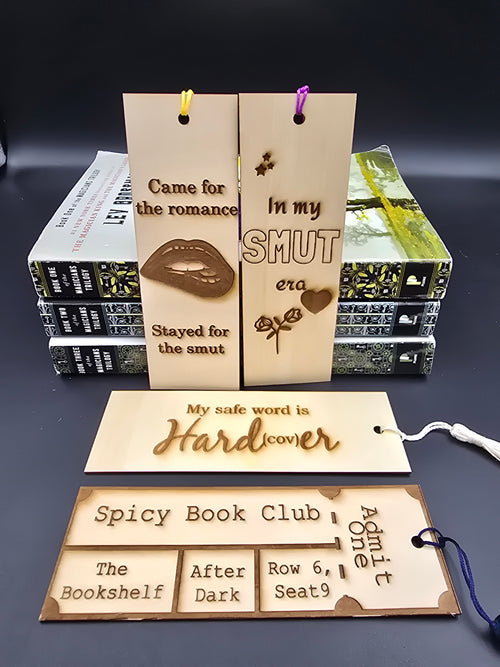 A collection of 4 laser engraved wooden bookmarks with colorful tassels that measure 6" x 2", standard bookmark size. Adult themed laser engraved phrases that read "came for the romance stayed for the smut" "in my smut era" "my safe word is hardcover" "spicy book club"