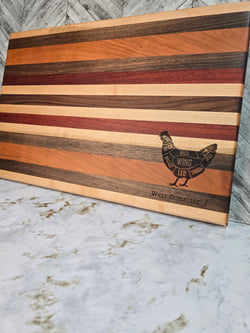 handcrafted wooden cutting board, made using walnut, cherry, red heart, and maple. laser engraved diagram of chicken cuts