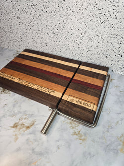 modern handcrafted wooden cheese board made from walnut, maple, cherry and padauk, built in silver cheese slicer, perfect for charcuterie, cheese, and appetizers. Laser engraved with the phrase "charcuterie french word for cheese and other fancy shit"